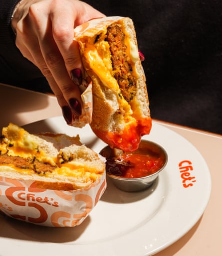 A meaty, cheesy concoction being dipped into a little dish of red sauce
