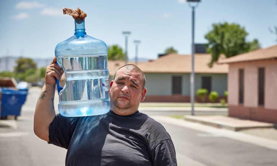 Rick Richo carries water to his home from a nearby water filling station during the mid day heat in Phoenix, AZ