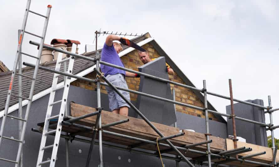 Builders attach rigid foam wall insulation sheets on a Victorian terraced house.