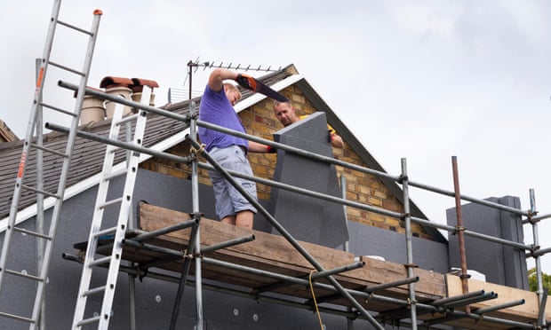 Builders fit rigid foam wall insulation sheets on to the gable end of a Victorian terraced house.
