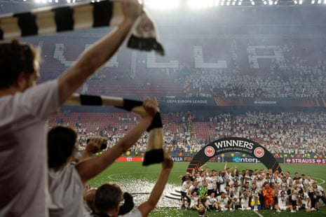 Eintracht Frankfurt players fans cheer their team as they pose with the trophy.