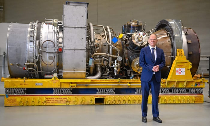 German Chancellor Olaf Scholz stands in front of a turbine of the Nord Stream 1 pipeline during a visit on August 3, 2022 at the plant of Siemens Energy in Muelheim an der Ruhr, western Germany, where the engine is stored after maintenance work in Canada