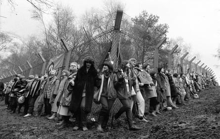 Women linking hands encircle the perimeter fence at Greenham