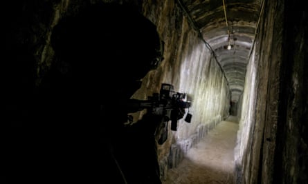A soldier points a gun down a Hamas tunnel in Gaza