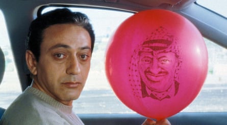 a man holds a balloon bearing the face of a man