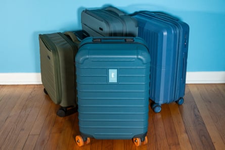 A group of four suitcases on ground next to blue wall