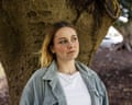 Shannon Stokes stand in front of a tree trunk, looking off to the side