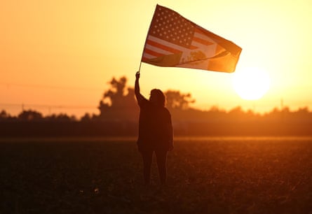 A woman waves an US-Mexican flag in a show of support for detainees during an immigration raid near Camarillo, California, on 10 July 2025.