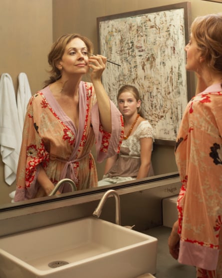 A mother applying makeup while her daughter watches