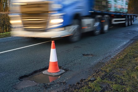 An HGV on a road with a cone covering a pothole