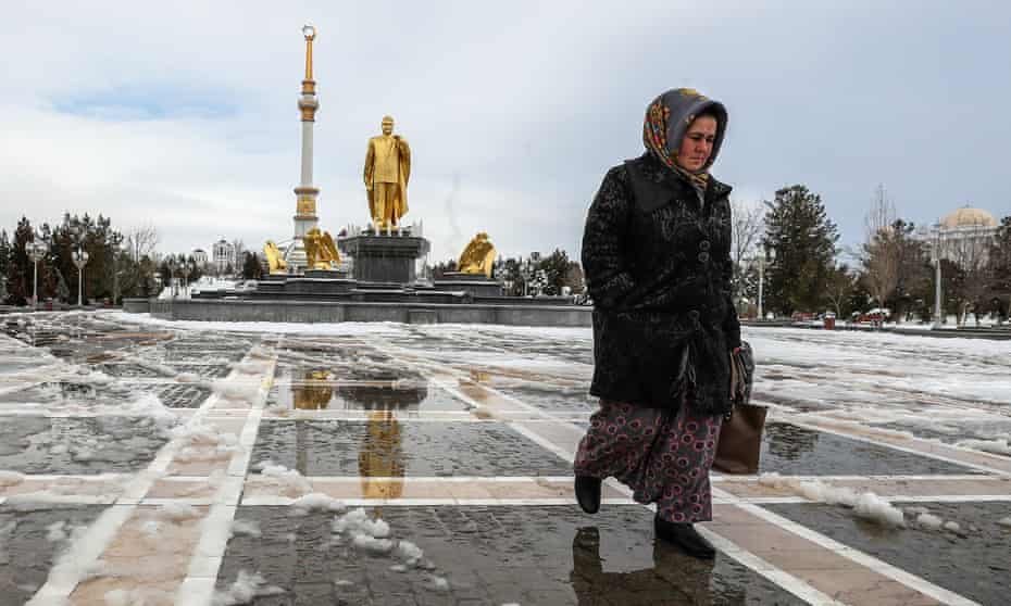 A woman walks past a gold statue of the first president of Turkmenistan, Saparmurat Niyazov, in the capital city of Ashgabat