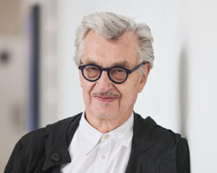 Film director Wim Wenders wearing black-rimmed glasses, a white shirt and black cardigan.