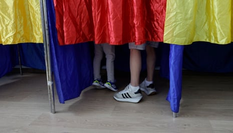 A Romanian man (R) accompanied by his son (L) stands inside a voting booth during the second round of presidential elections at a polling station in Bucharest, Romania.