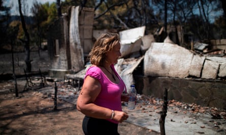 A woman walks in front of her destroyed house in the village of Neos Voutzas, near Athens.