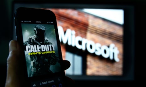 Activision's Call of Duty on a smartphone near a photograph of the Microsoft logo