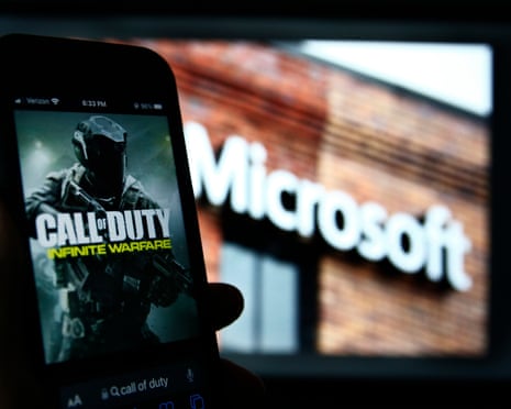 Activision's Call of Duty on a smartphone near a photograph of the Microsoft logo