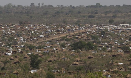 A view of huts and scrubland with a dirt road running through them.