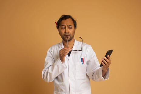 Rhik wearing a lab coat holding glasses and a phone, against an orange background
