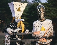 Two people dresked in polka-dot costumes wearing polka-dot headwear with a field behind them