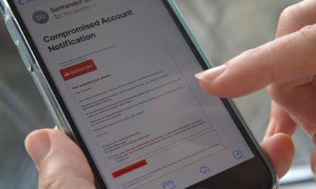 Celular na mão de uma mulher com um e-mail de phishing, supostamente do banco Santander, exibido na tela