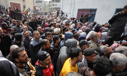 A crowd of people around a warehouse to receive vital food and supplies