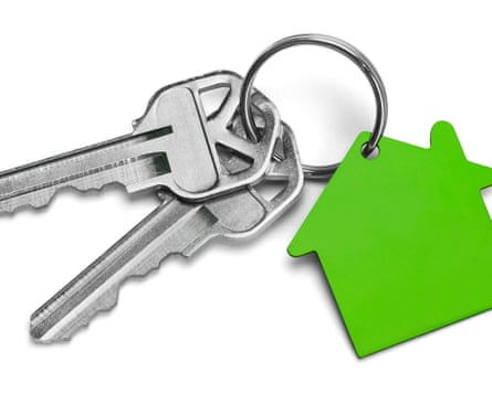 a set of keys with a green house shape as the key ring badge