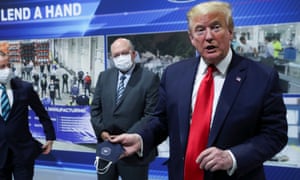 Donald Trump holds a protective face mask with a presidential seal on it that he said he had been wearing earlier in his tour.