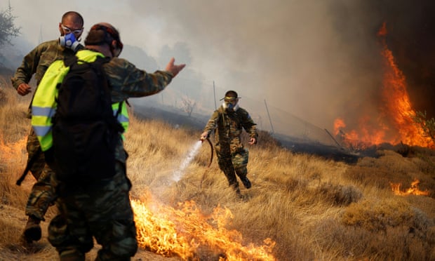 Volunteers try to extinguish a wildfire burning in the village of Markati, near Athens, on 16 August. 