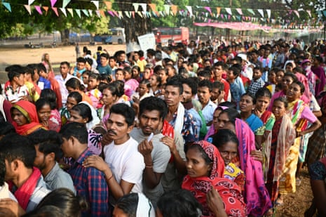 Separate lines of Indian men and women queueing under lines of bunting