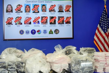 A photo of former Canadian Olympic snowboarder Ryan Wedding, 43, who is a fugitive, is seen top left, with 15 other defendants who have been charged with allegedly running and participating in a transnational drug trafficking operation, is displayed on a video monitor at a news conference at the FBI offices in Los Angeles on Thursday.