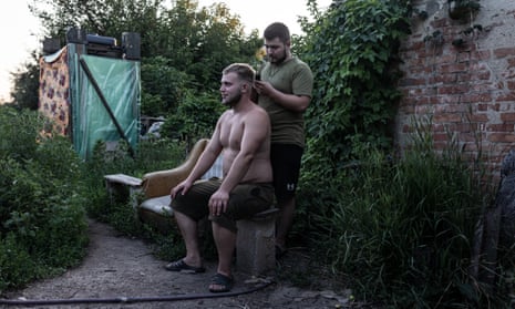 A Ukrainian soldier cuts another soldier's hair in a house far from the frontline in Donetsk oblast, Ukraine.