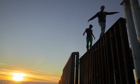 Migrants on the the border structure separating Mexico and the USA near Tijuana.