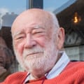 Headshot of a bald man in a red jumper