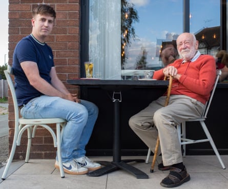 Two men sitting opposite each other at a table outside a restaurant
