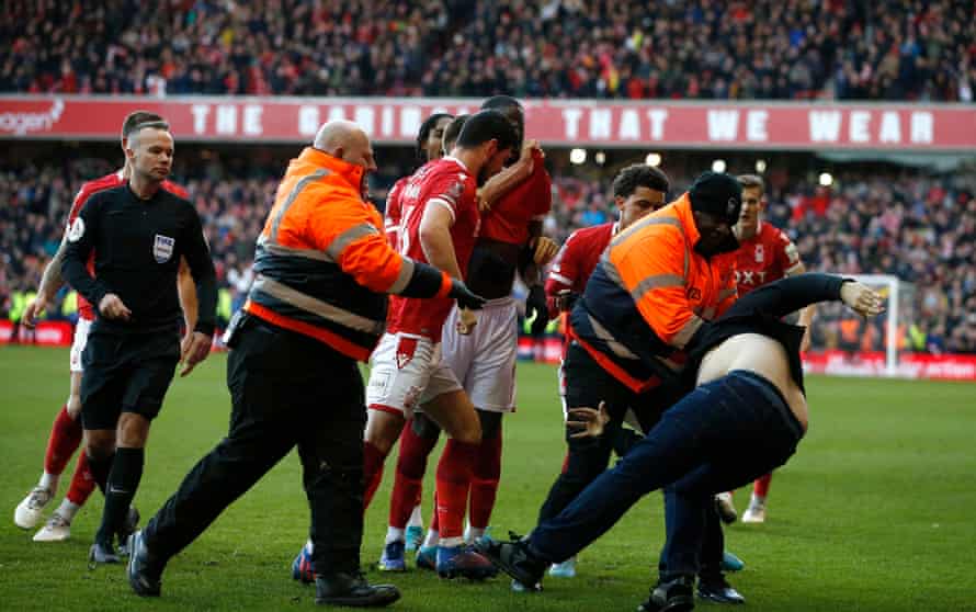 A Leicester City fan is detained by stewards after invading the pitch.