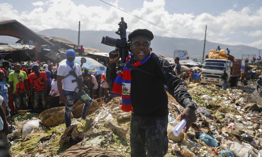 Barbecue, the leader of the ‘G9 and Family’ gang, stands next to garbage to call attention to the conditions people live in as he leads a march against kidnapping through La Saline neighborhood in Port-au-Prince in October 2021.