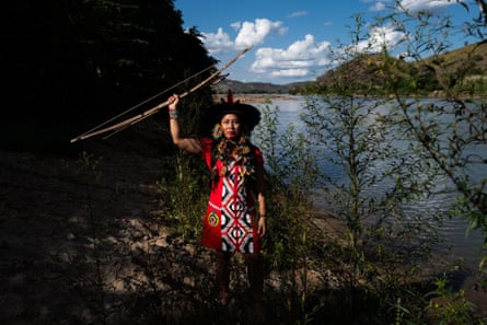 واكريوا كريناك، زعيم المجتمع المحلي، يرتدي الملابس التقليدية ويقف بذراعه المرفوعة على ضفة نهر ريو دولتشي، في منطقة كريناك الأصلية.