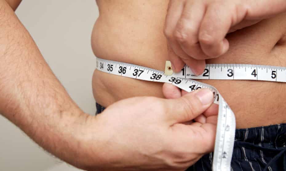 Close-up of man measuring waist with tape measure. 