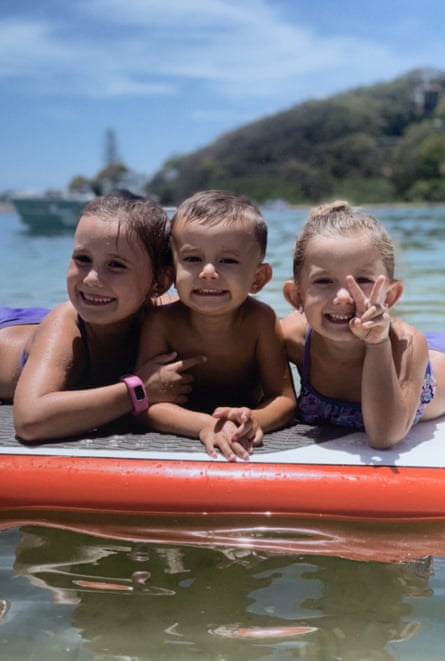 The three children float on a board in the ocean