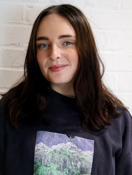 Jess Mallaghan stands near a wall wearing a T-shirt