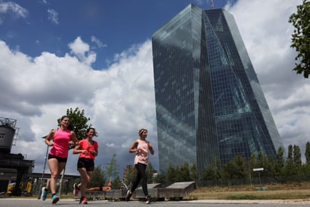 Joggers pass the European Central Bank building in Frankfurt, Germany.