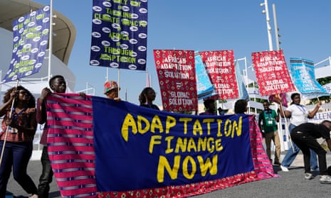 Activists participate in a demonstration with a sign that reads ‘adaptation finance now’ .