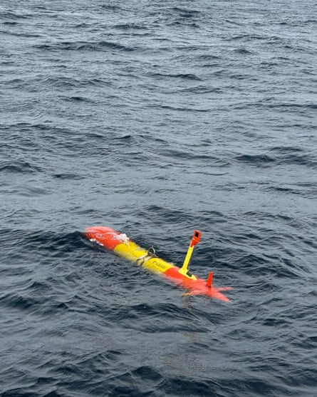 An orange and yellow torpedo-shaped instrument floating on the sea’s surface