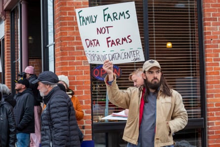A man holds up a handwritten poster saying ‘Family farms not data farms