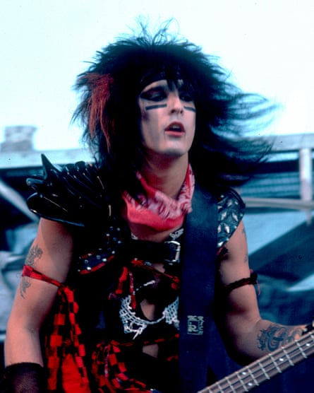 Nikki Sixx in very very heavy black makeup, red bandanna, leather studded vest, tribal stripes and huge black hair