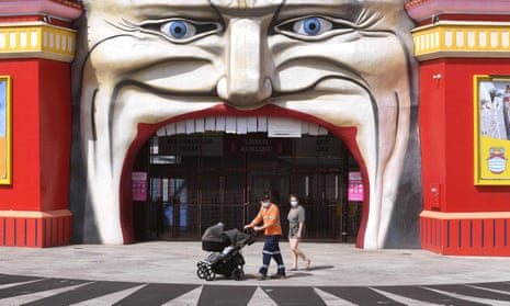 A family walk past the entrance to Luna Park in the Melbourne during lockdown 