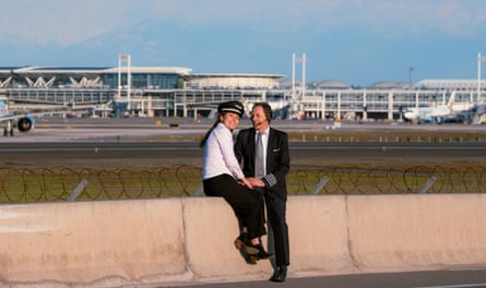 Alfredo and Carolina sit on a wall at an airport