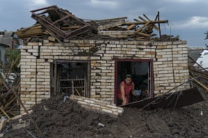 Neighbour Olga Rudneva recovers an item for the elderly owner of a home damaged by a rocket strike in Druzhkivka as Russian shelling continued to hit towns and villages in the province of Donetsk
