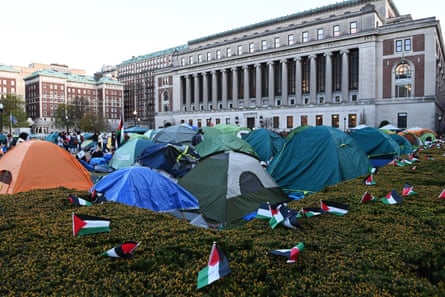 small palestinian flags surround tents on the grass outside a large academic building with columns