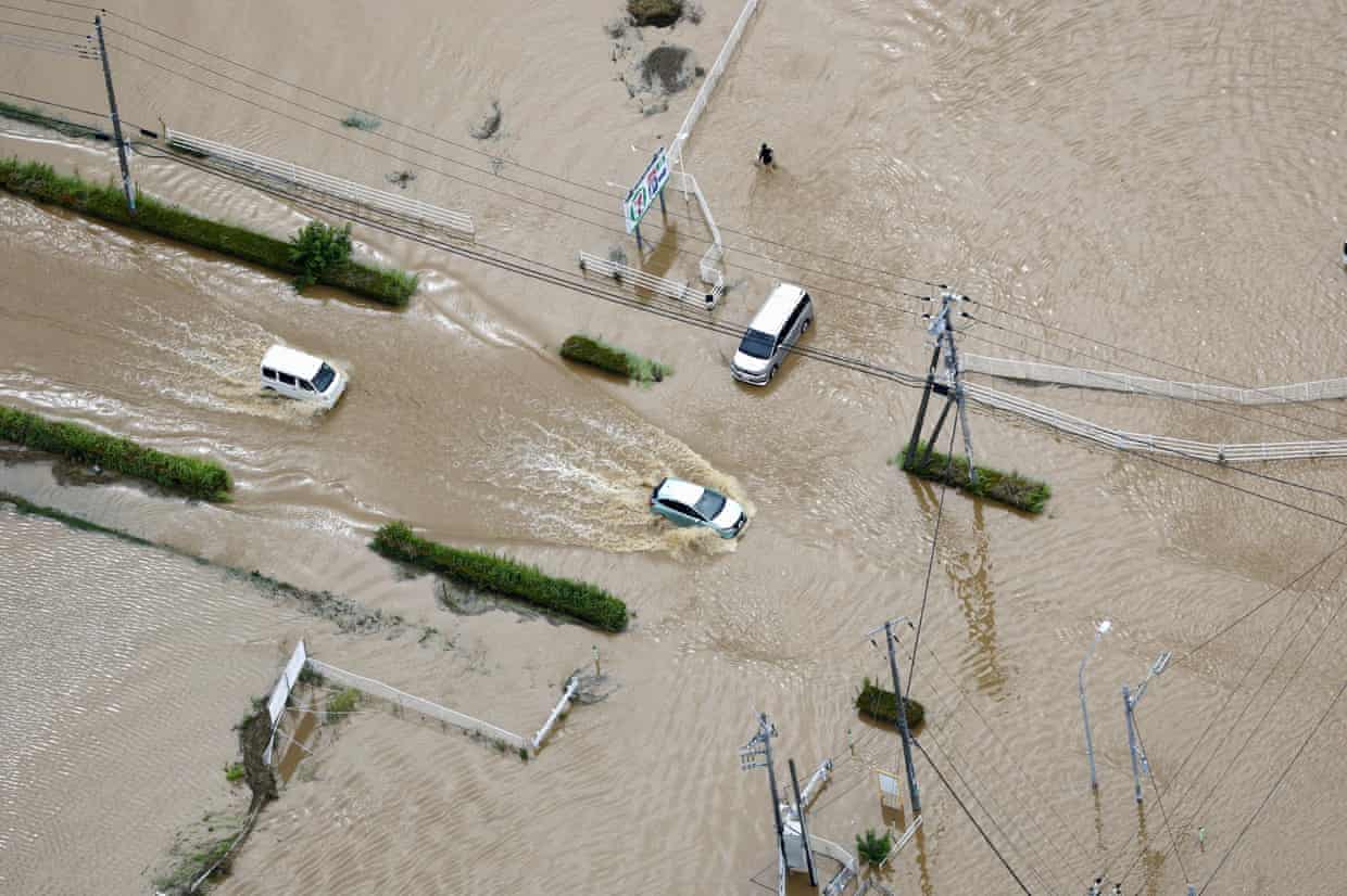 Cars struggling to drive through roads completely covered in brown flood water